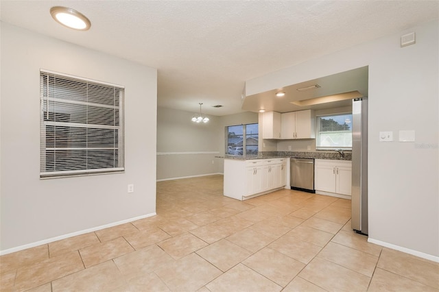 kitchen with light tile patterned floors, white cabinetry, stainless steel appliances, and a chandelier