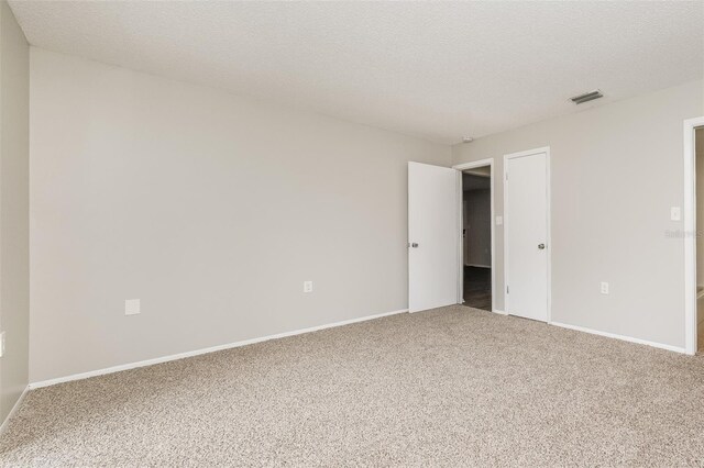 carpeted empty room featuring a textured ceiling