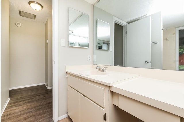 full bath featuring wood finished floors, visible vents, vanity, and baseboards