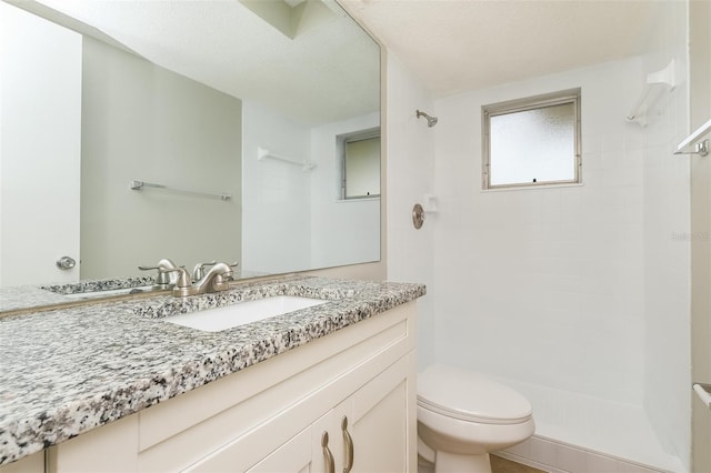 bathroom featuring tiled shower, toilet, and vanity