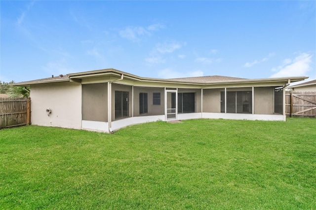 back of house with a sunroom, a lawn, and a fenced backyard