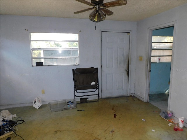 interior space with ceiling fan and a textured ceiling