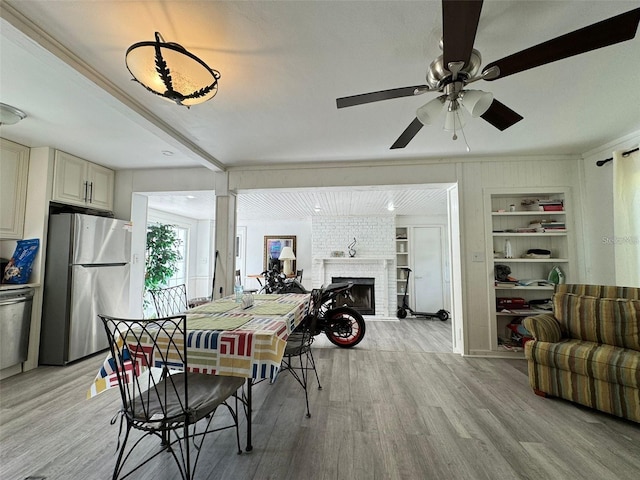 dining room with ornamental molding, built in features, a fireplace, light hardwood / wood-style floors, and ceiling fan