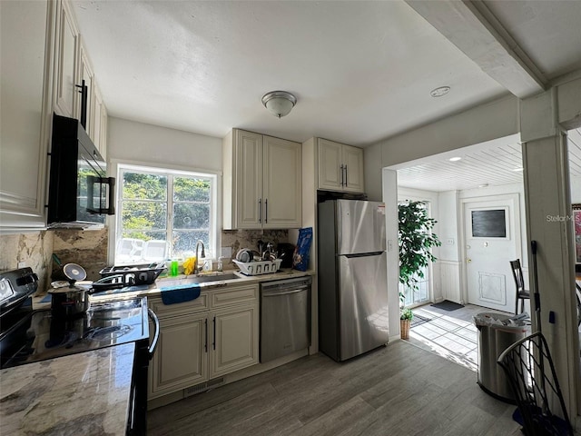 kitchen with decorative backsplash, hardwood / wood-style floors, black appliances, and sink