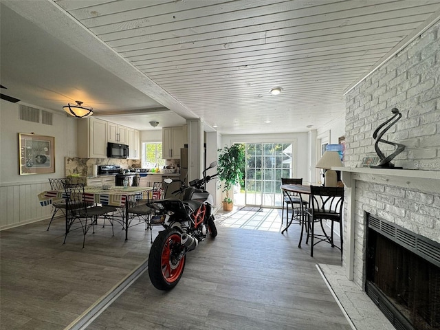 dining space with a fireplace, wood-type flooring, and plenty of natural light