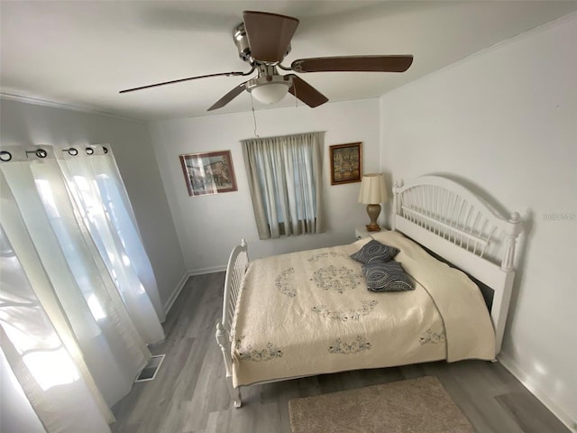 bedroom with crown molding, wood-type flooring, and ceiling fan