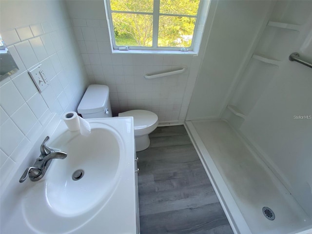 bathroom with hardwood / wood-style flooring, toilet, sink, tile walls, and walk in shower