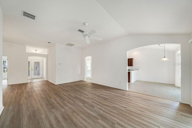 unfurnished living room with vaulted ceiling, wood-type flooring, and ceiling fan