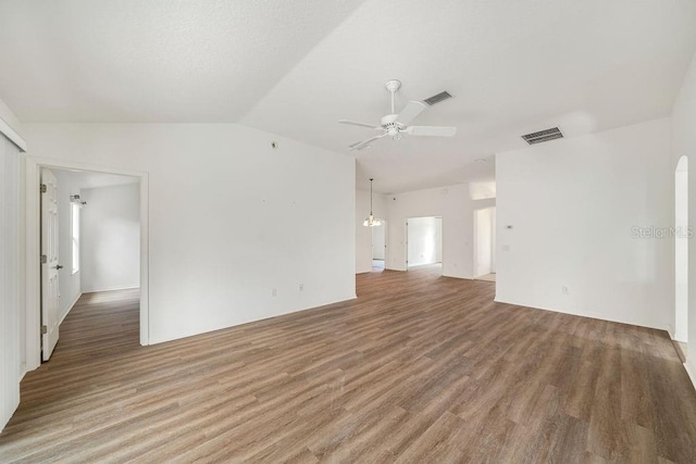 unfurnished living room with hardwood / wood-style flooring, ceiling fan with notable chandelier, and vaulted ceiling