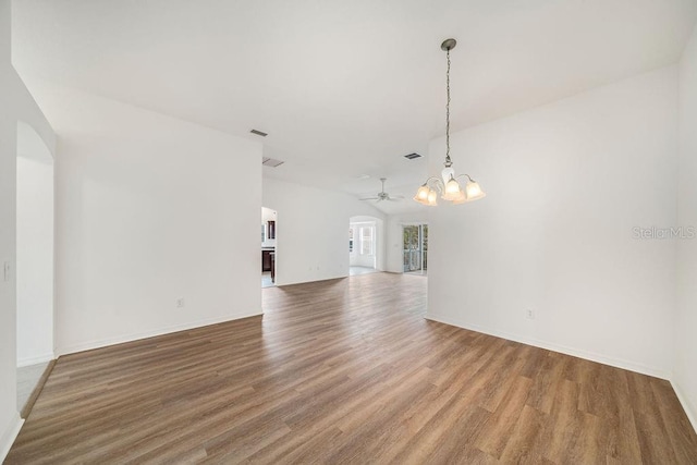 spare room featuring ceiling fan with notable chandelier and hardwood / wood-style floors