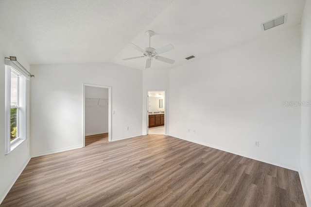 unfurnished room with ceiling fan, lofted ceiling, and light wood-type flooring