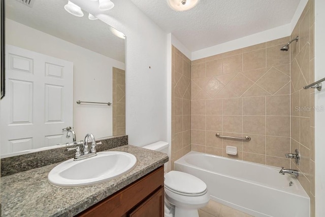 full bathroom featuring toilet, tile patterned flooring, tiled shower / bath combo, vanity, and a textured ceiling