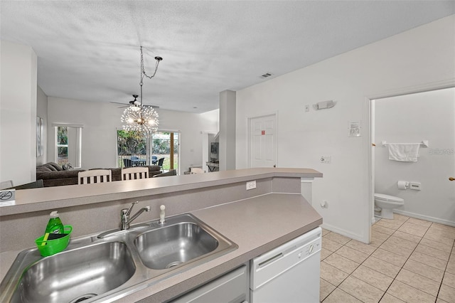 kitchen with light tile patterned floors, a textured ceiling, a chandelier, dishwasher, and sink