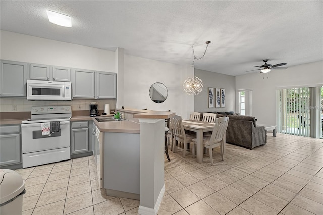 1029 Park Ridge Cir, Kissimmee, FL 34746 - kitchen with white appliances, gray cabinets, open floor plan, a peninsula, and light tile patterned floors