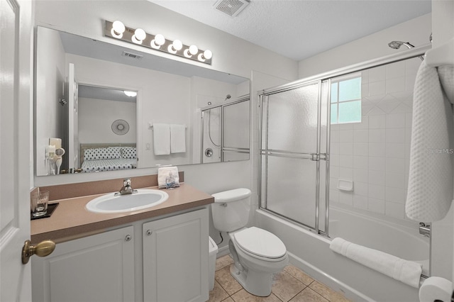 1029 Park Ridge Cir, Kissimmee, FL 34746 - ensuite bathroom featuring toilet, vanity, enclosed tub / shower combo, tile patterned flooring, and a textured ceiling
