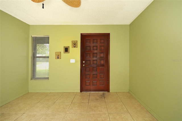 tiled entrance foyer featuring a textured ceiling and ceiling fan