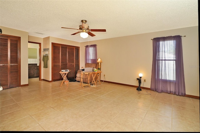 living area with light tile patterned flooring, a textured ceiling, and ceiling fan