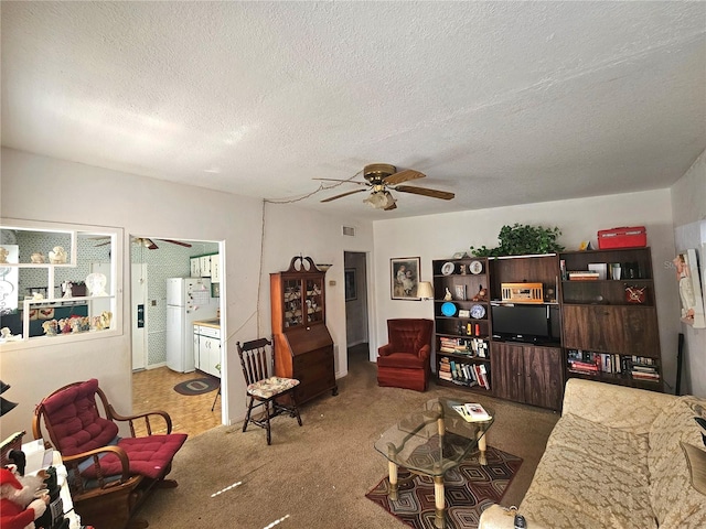 living room with a textured ceiling, carpet, and ceiling fan