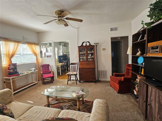 living room with ceiling fan, a textured ceiling, and light colored carpet