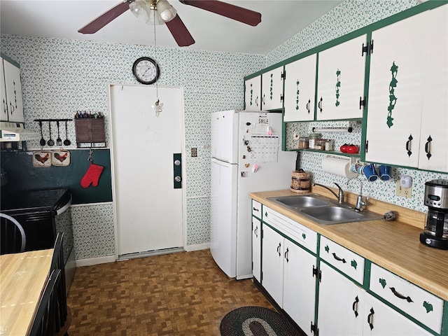 kitchen with black range with electric stovetop, exhaust hood, white cabinetry, white fridge, and sink