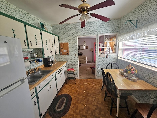 kitchen with white cabinetry, ceiling fan, sink, and white refrigerator