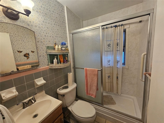 bathroom with tile walls, vanity, toilet, and an enclosed shower