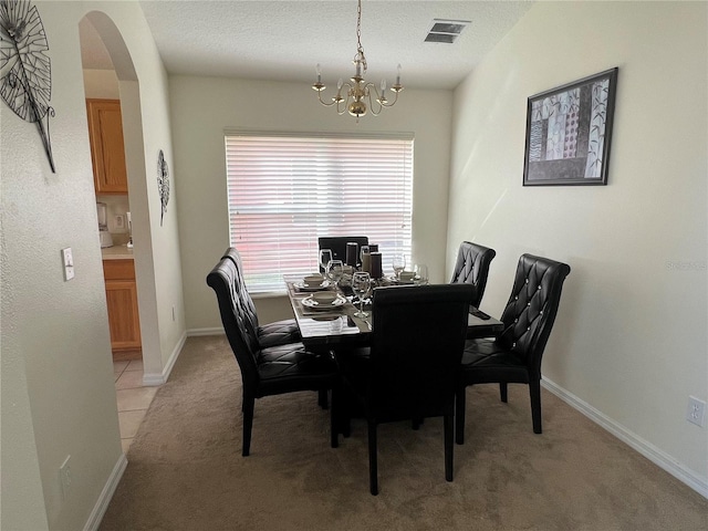dining area with visible vents, light carpet, an inviting chandelier, and arched walkways