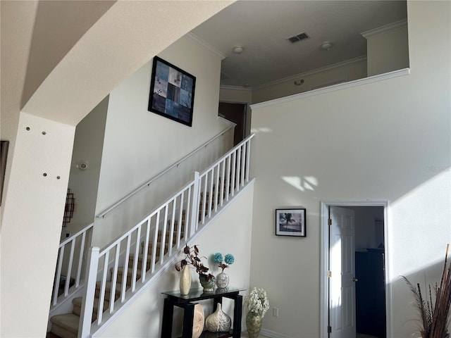 stairs with visible vents and crown molding