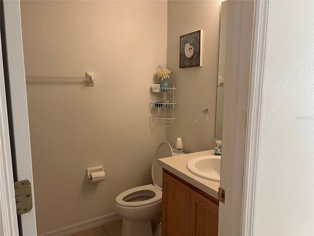 half bathroom with toilet, tile patterned flooring, and vanity