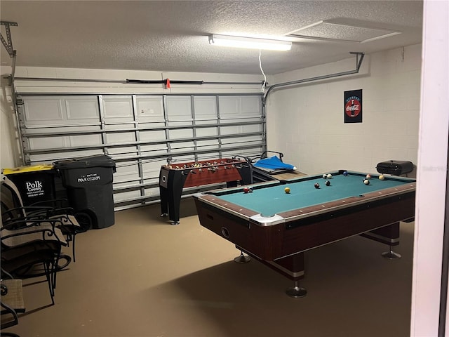recreation room featuring pool table, concrete block wall, concrete flooring, a textured ceiling, and a garage