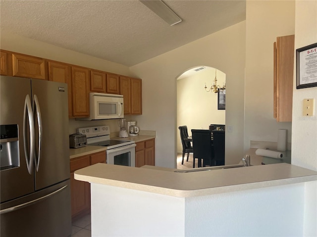 kitchen with light countertops, an inviting chandelier, brown cabinets, and white appliances