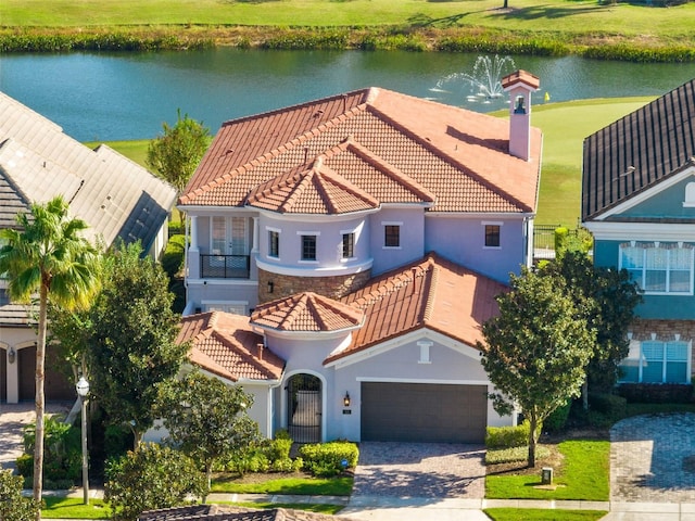 mediterranean / spanish-style house with a water view, a front lawn, and a garage