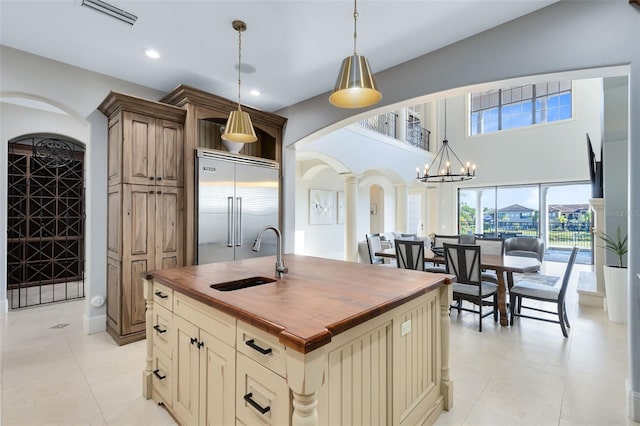 kitchen featuring sink, wood counters, built in fridge, ornate columns, and pendant lighting