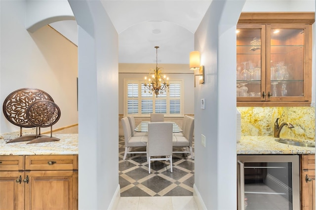 dining space with indoor wet bar, beverage cooler, vaulted ceiling, light tile patterned flooring, and a notable chandelier