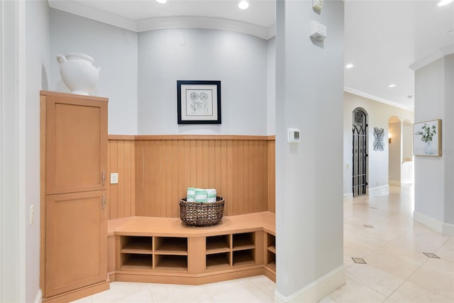 interior space featuring wood walls, crown molding, and light tile patterned floors