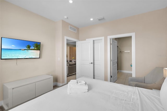 bedroom featuring a walk in closet, a closet, and light tile patterned floors