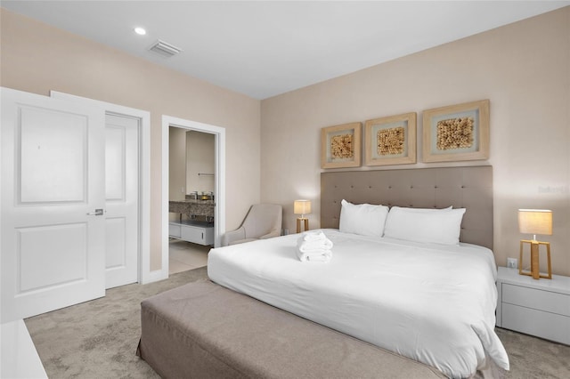 bedroom featuring ensuite bath and light colored carpet