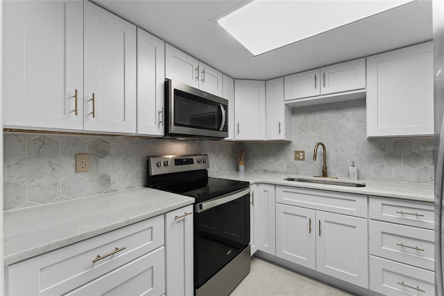 kitchen featuring white cabinets, appliances with stainless steel finishes, tasteful backsplash, and sink