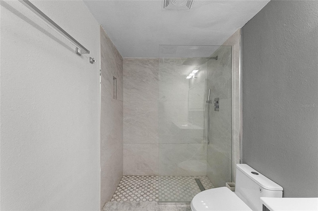 bathroom with tiled shower and toilet