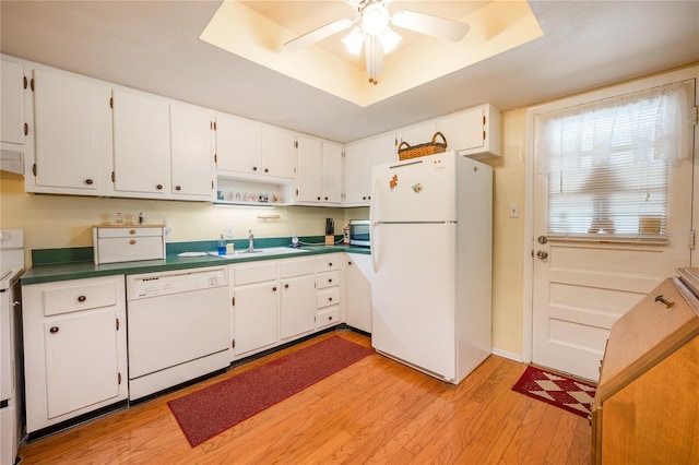 kitchen with white appliances, a raised ceiling, ceiling fan, light hardwood / wood-style flooring, and white cabinetry