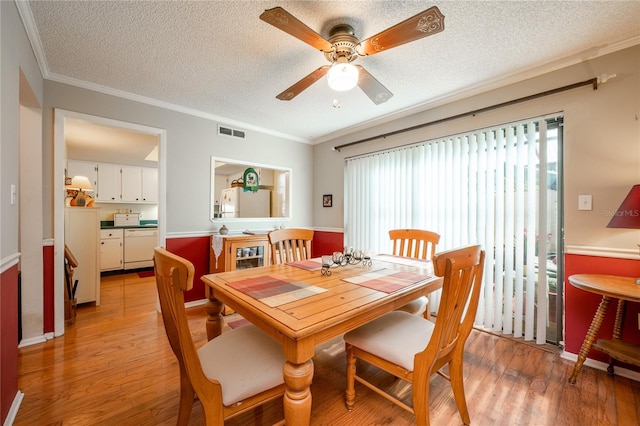 dining room featuring ceiling fan, light hardwood / wood-style flooring, a textured ceiling, and ornamental molding