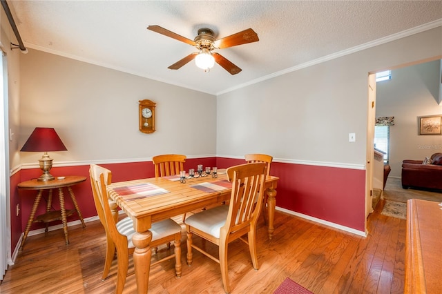 dining area featuring crown molding, ceiling fan, a textured ceiling, and hardwood / wood-style flooring