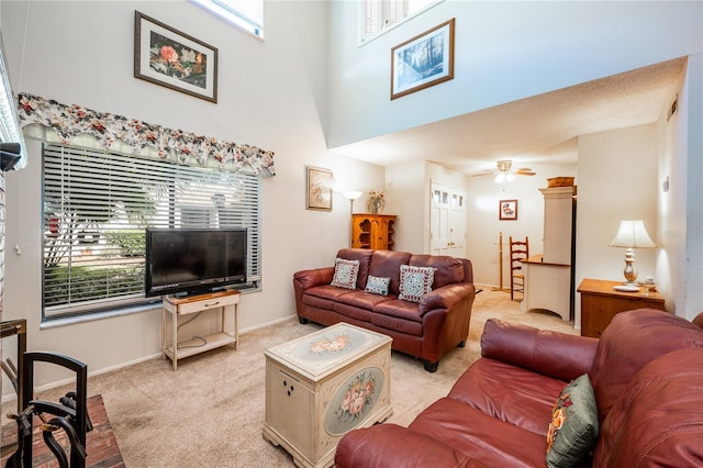 living room featuring a high ceiling, light colored carpet, and ceiling fan