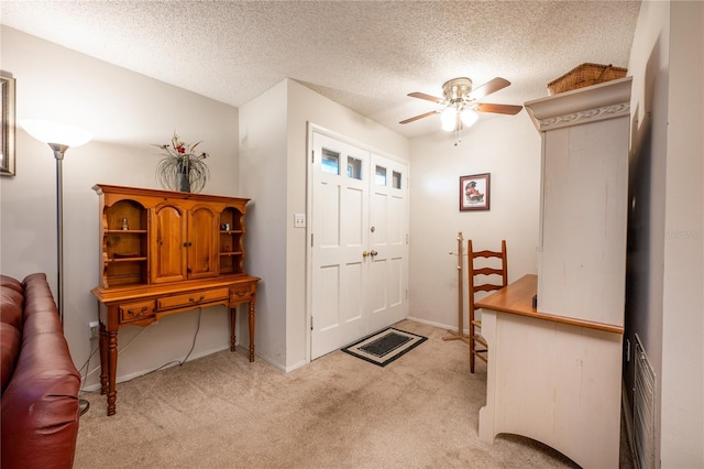 carpeted foyer entrance featuring ceiling fan and a textured ceiling