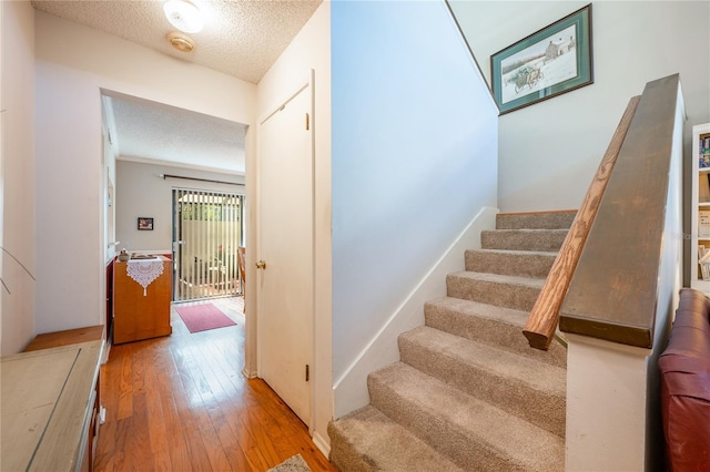 stairway with hardwood / wood-style flooring and a textured ceiling