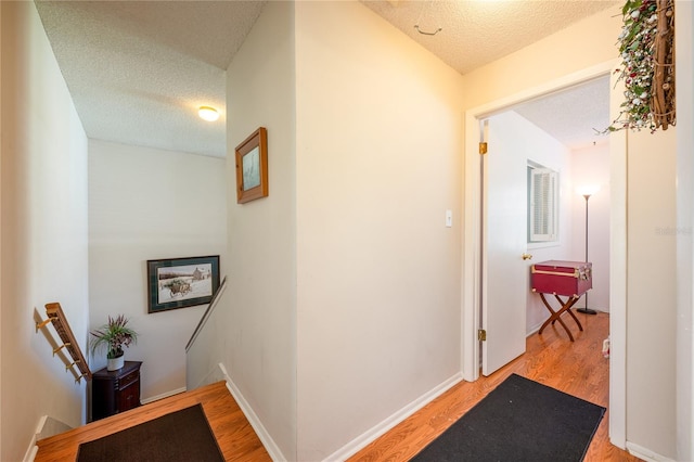 hallway featuring light hardwood / wood-style floors and a textured ceiling