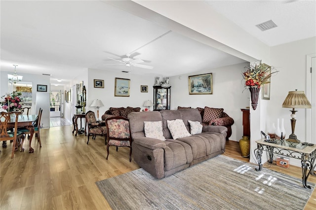 living room with light hardwood / wood-style flooring and ceiling fan with notable chandelier