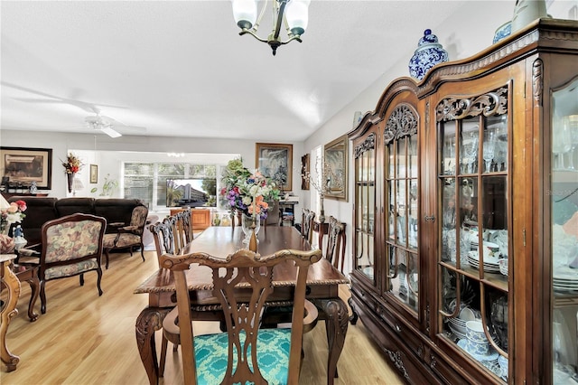 dining area with ceiling fan with notable chandelier and light hardwood / wood-style floors