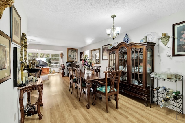 dining room featuring a textured ceiling, an inviting chandelier, and light wood-type flooring