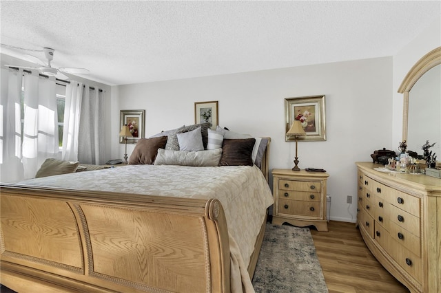 bedroom featuring a textured ceiling, light wood-type flooring, and ceiling fan